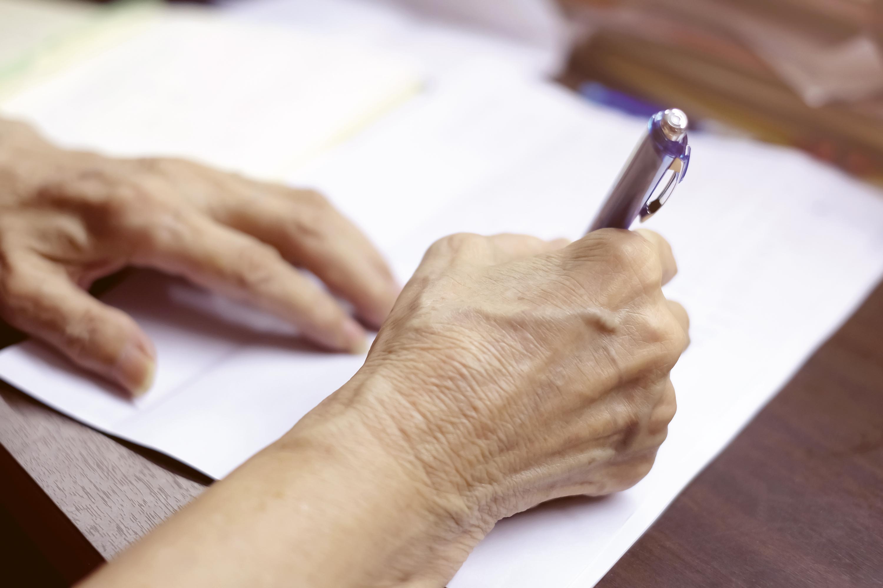Eine Person die ein Formular per Hand ausfüllt