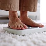 Gewichtsverlust im Alter muss unter Umständen überprüft werden. Ältere Frau steht auf der Wage