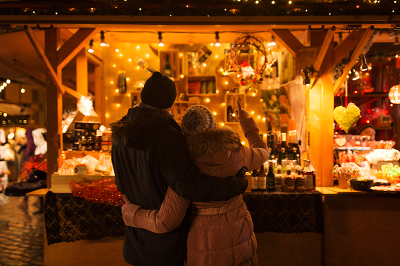 Älteres Paar steht vor einem Stand auf dem Weihnachtsmarkt.