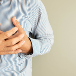 Man fasst an die Brust, weil er Herzschmerzen hat.