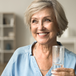 Eine Frau hält ein Glas Wassser und lächelt