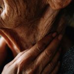 Berührung im Alter - Frau die sich am Hals berührt