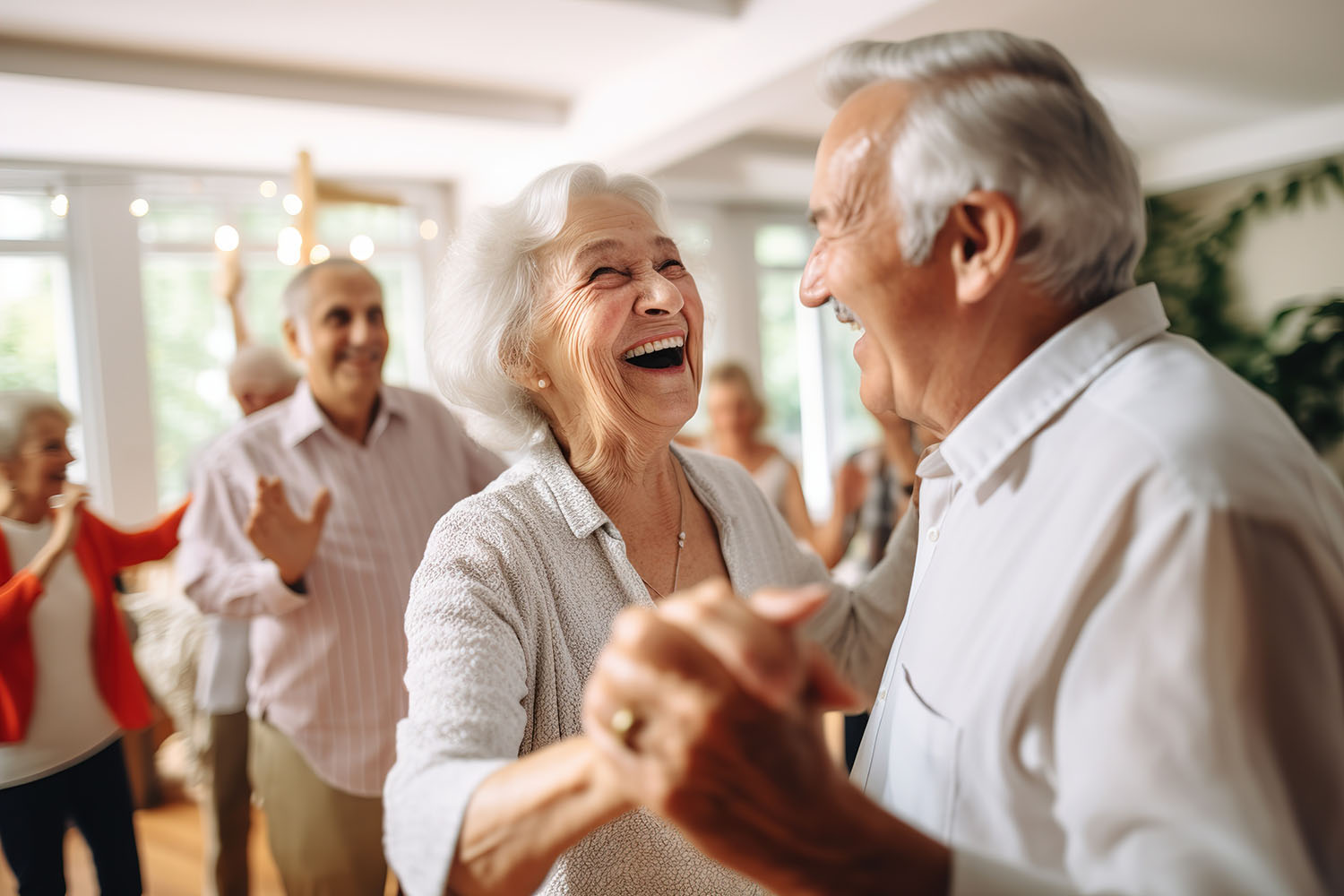 An elderly couple is dancing at a house party in an apartment for elderly friends, smiling and enjoying chatting with friends. Time for the elderly. Lachende ältere Menschen beim Tanzen