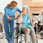 Pflegerin redet mit älterer Frau auf dem Rollstuhl