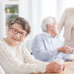 Ältere Menschen sitzen an einem Tisch mit Kuchen und tauschen sich aus.