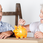 2 ältere Menschen werfen Geld in ein Sparschwein