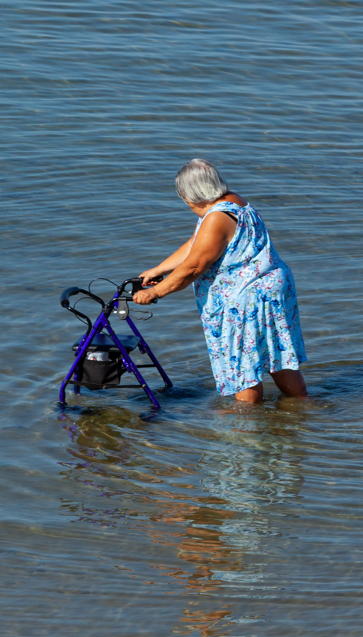 Frau mit Rollator im Wasser bis zu den Knien