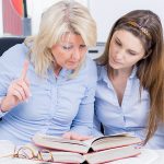Ältere und jüngere Frau studieren dicke Gesetzesbücher